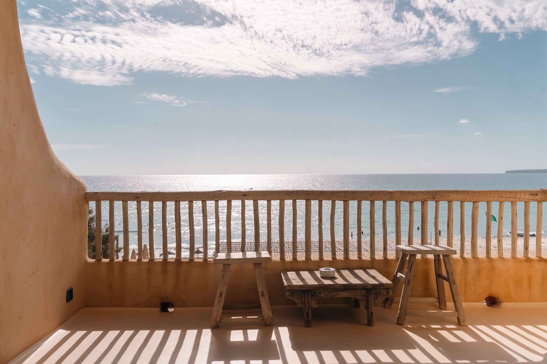 Sea-view terrace at Hannah Formentera with a rustic timber balustrade above the beach at Es Arenals | The Aficionados