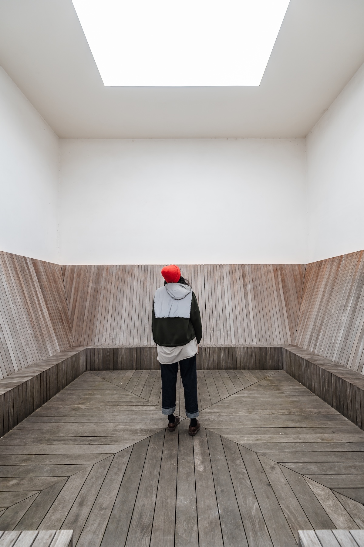 Visitor beneath a skylight in a timber-lined viewing room, Antwerp Zuid | The Aficionados
