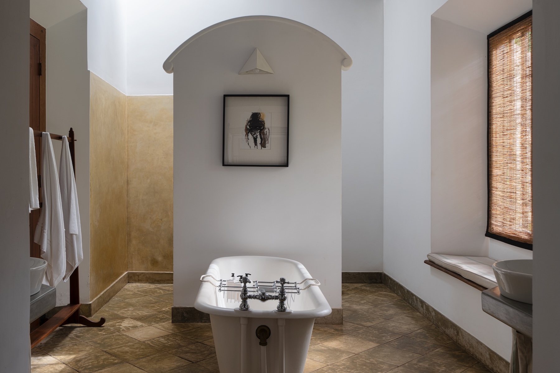 Freestanding rolltop bathtub set within a vaulted alcove beneath a framed figurative work on paper from Peter Harris's collection, bathroom at Doornberg, the 18th-century Dutch colonial villa above Galle, Sri Lanka | The Aficionados.