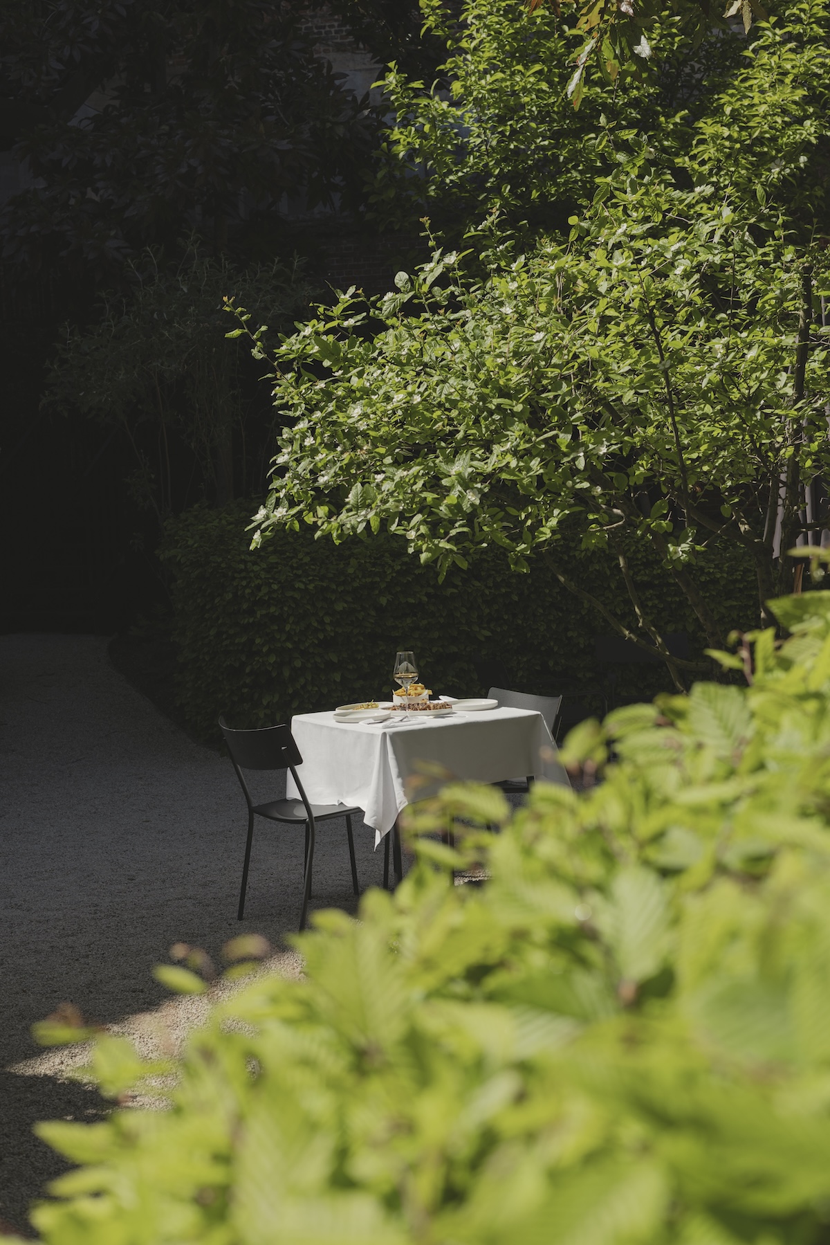 A table for two set among the greenery of the secret garden at August, Antwerp | The Aficionados