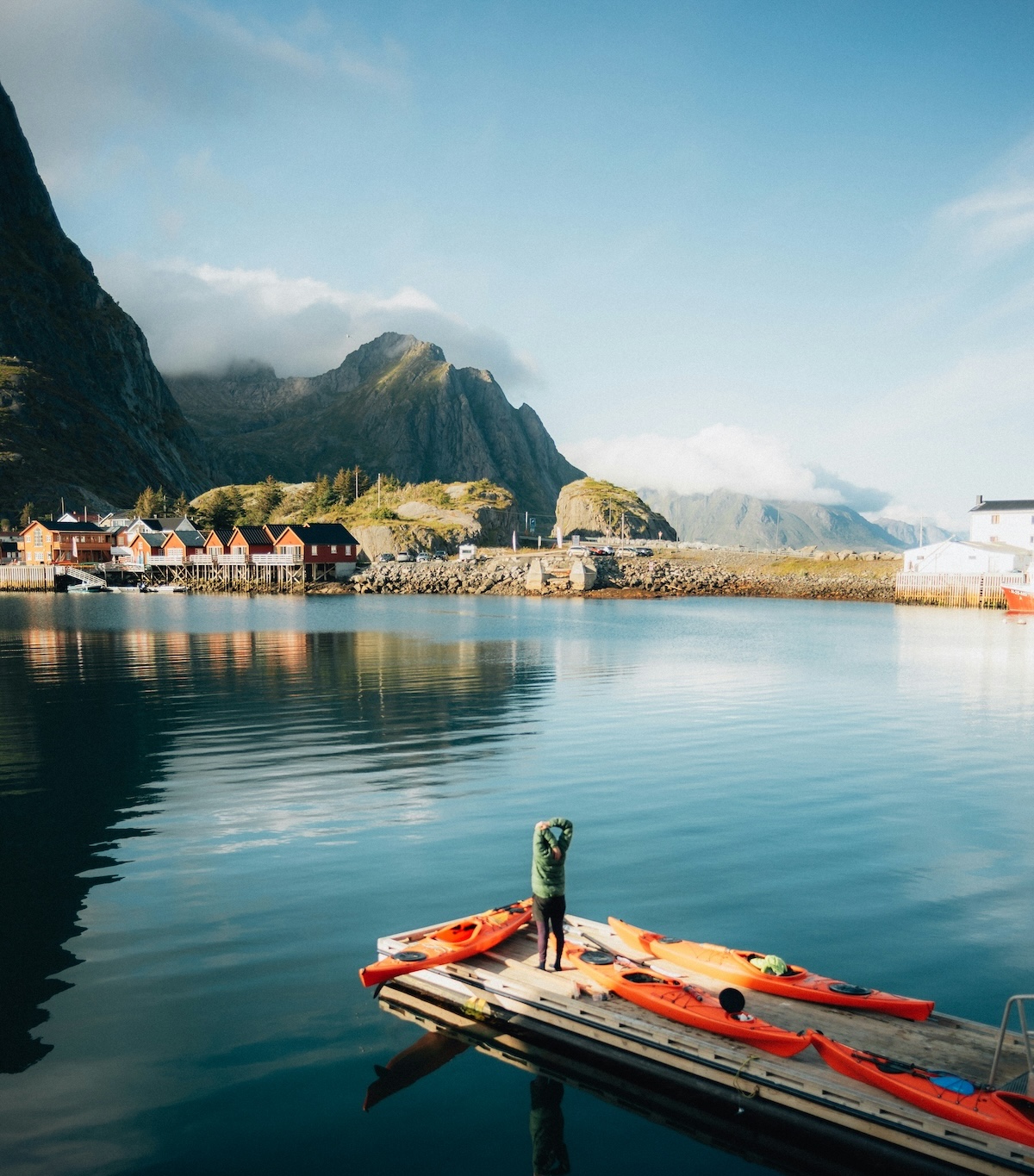 Sea kayaks on the harbour pontoon at Nusfjord, Lofoten, with rorbuer and mountains mirrored in glassy water | The Aficionados