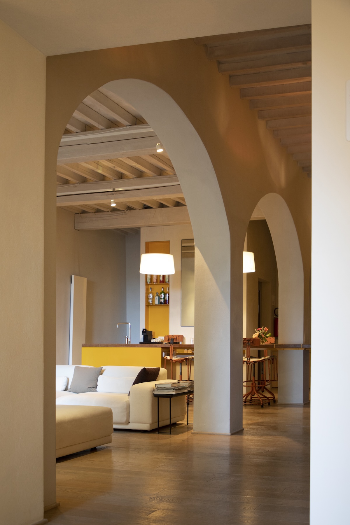Vaulted arches and beamed ceilings at La Bandita Townhouse, opening onto a white sofa and a lemon yellow kitchen | The Aficionados