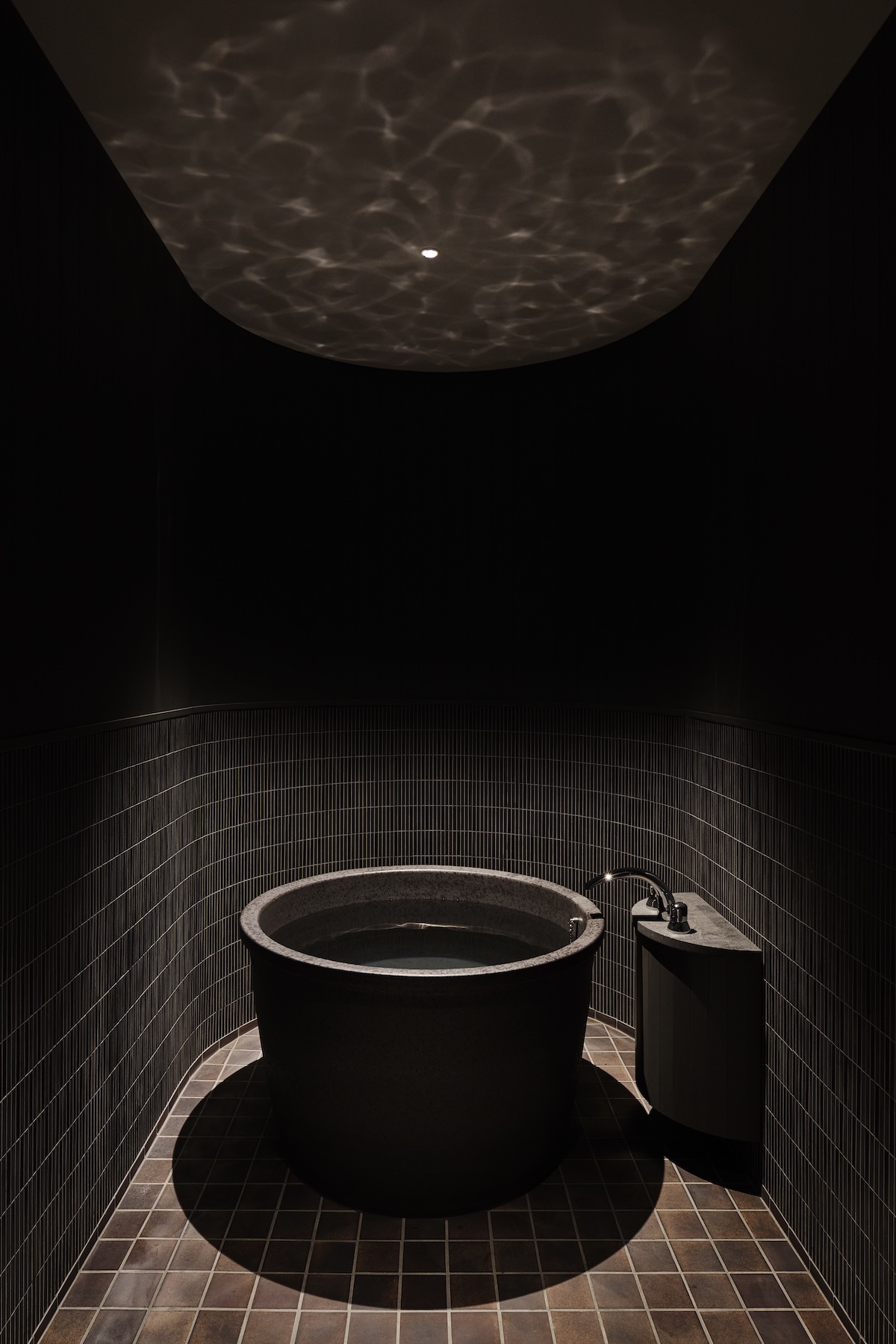 Stone soaking tub at Né beneath rippling water-light reflections on the ceiling, intimate bathing chamber, Shibata, Niigata, Japan | The Aficionados.