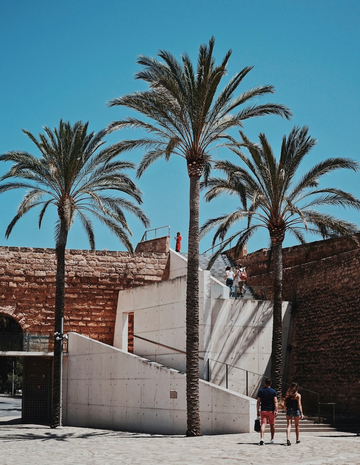 Visitors on the white concrete ramp at Es Baluard, set against the sandstone wall of the bastion of Sant Pere | The Aficionados