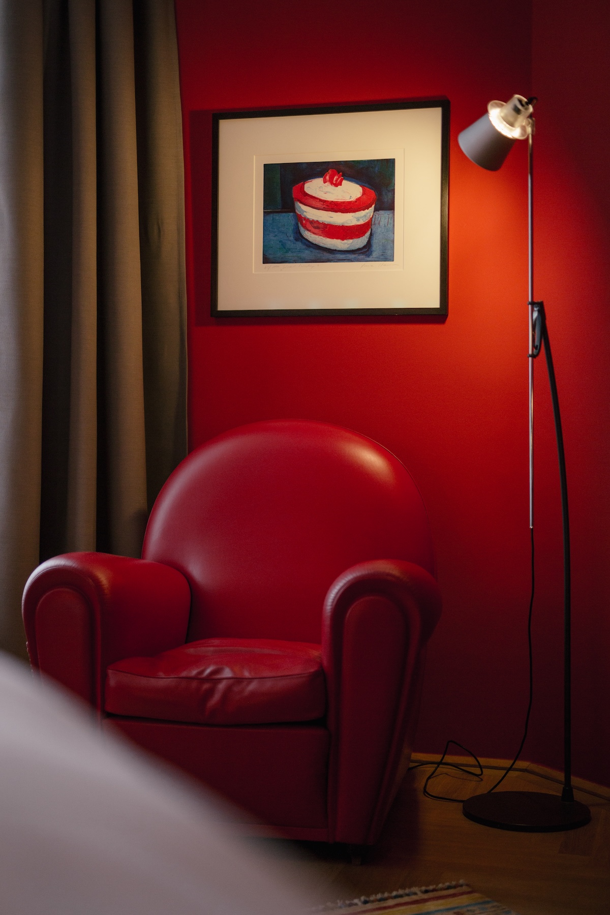 A red leather armchair below Xenia Hausner's cake painting, in the bedroom of the Harry K Room at Hotel Altstadt Vienna | The Aficionados.