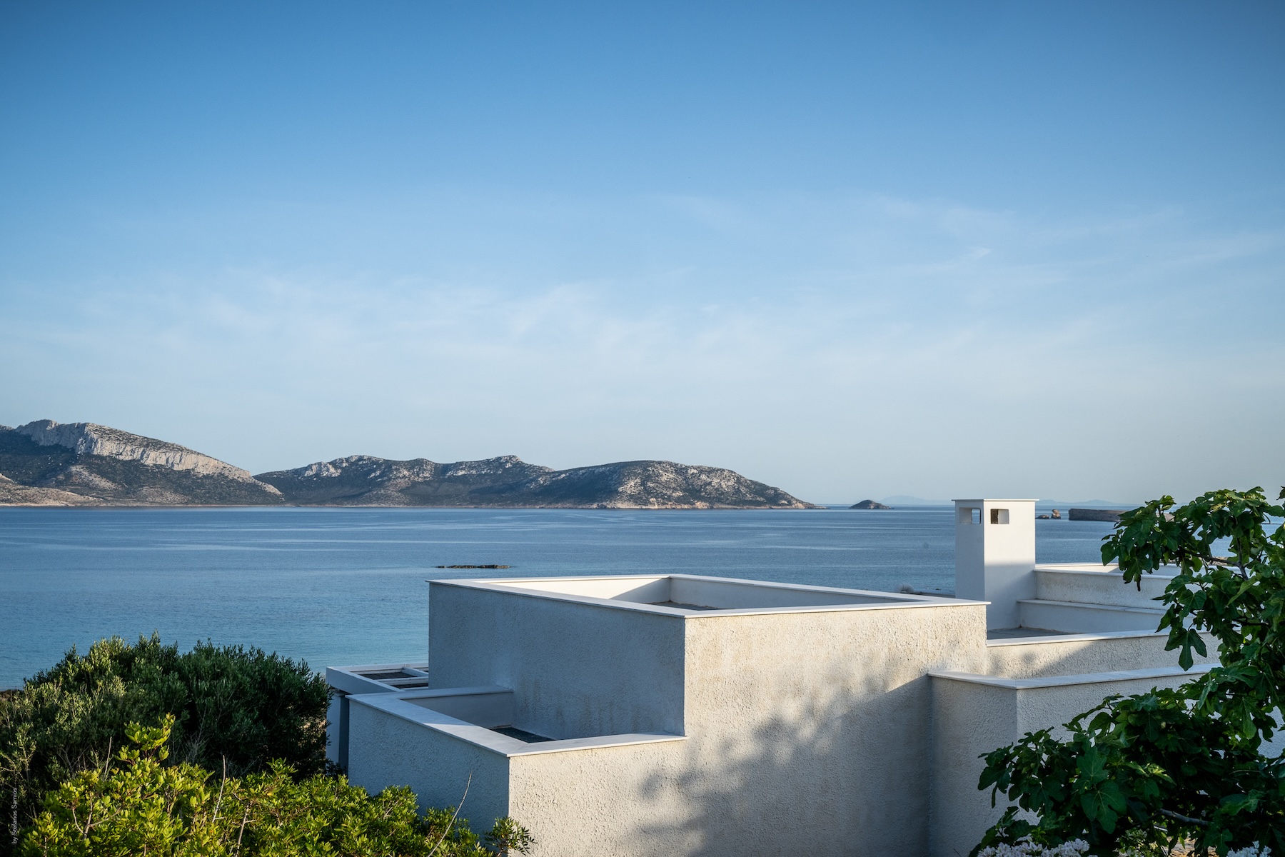 A cubic, whitewashed Cyclades-style villa at Éros Kéros looking across the bay to the hills, boutique design houses on the slow island of Koufonisia.