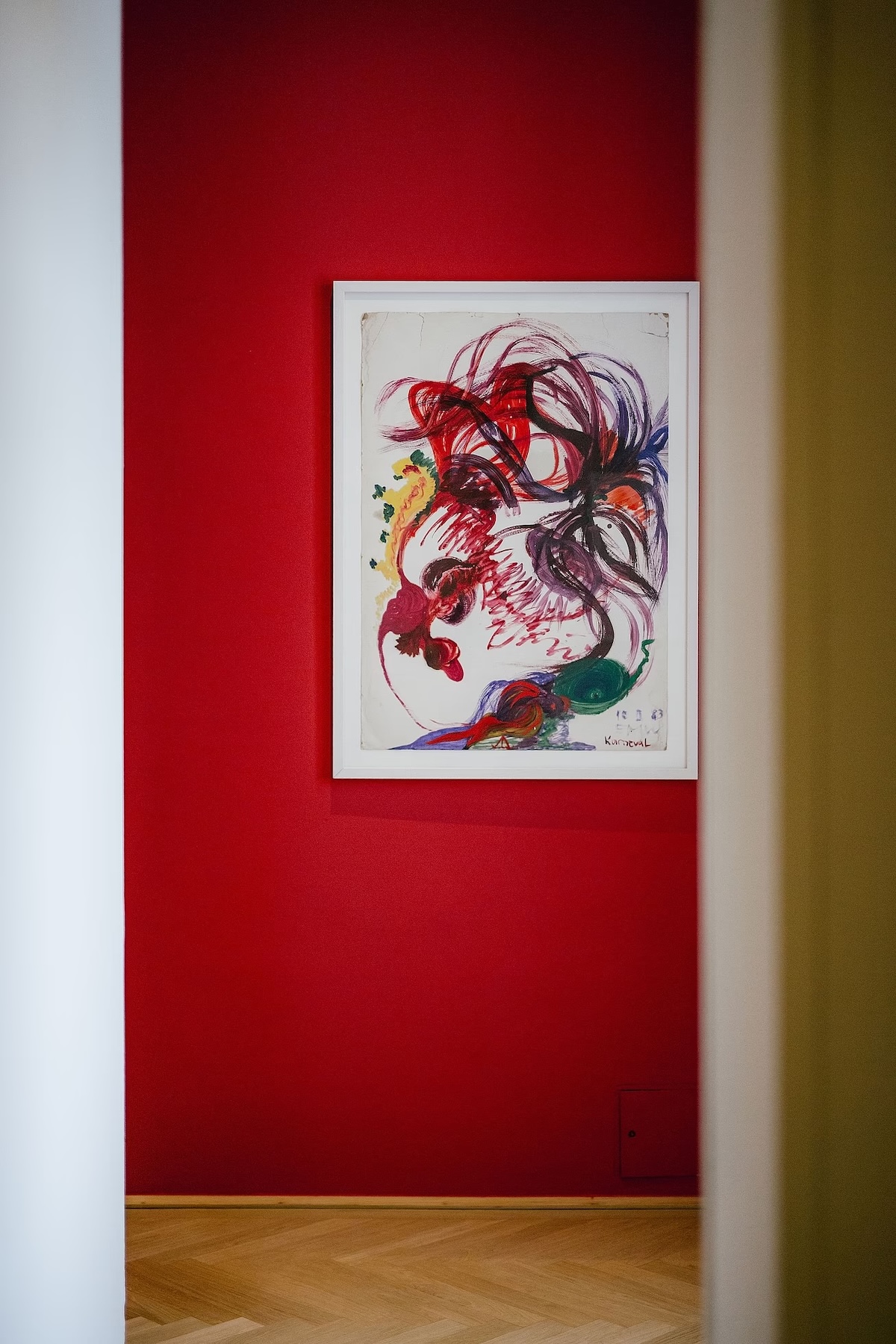 A framed gestural painting titled Karneval on the deep red wall of the Harry K Room at Hotel Altstadt Vienna | The Aficionados.