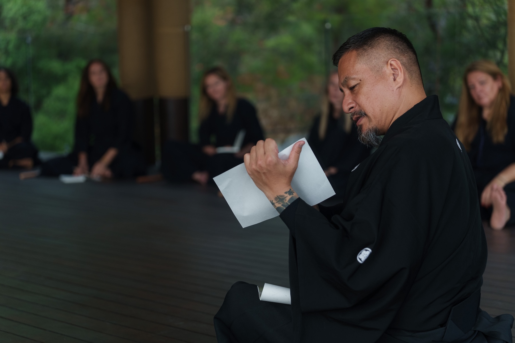 Sensei Zen Takai kneels in seiza holding calligraphy paper during an energy control practice, guiding participants at the Zen Samurai retreat in Turkey.