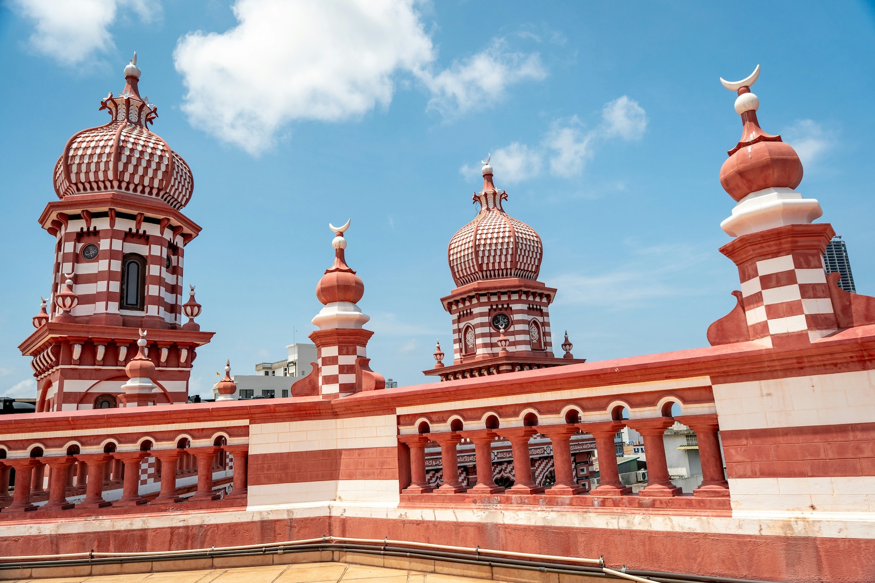 Candy-striped red-and-white domes and minarets of the Jami-Ul-Alfar Red Mosque against a blue sky, Pettah, Colombo, Sri Lanka