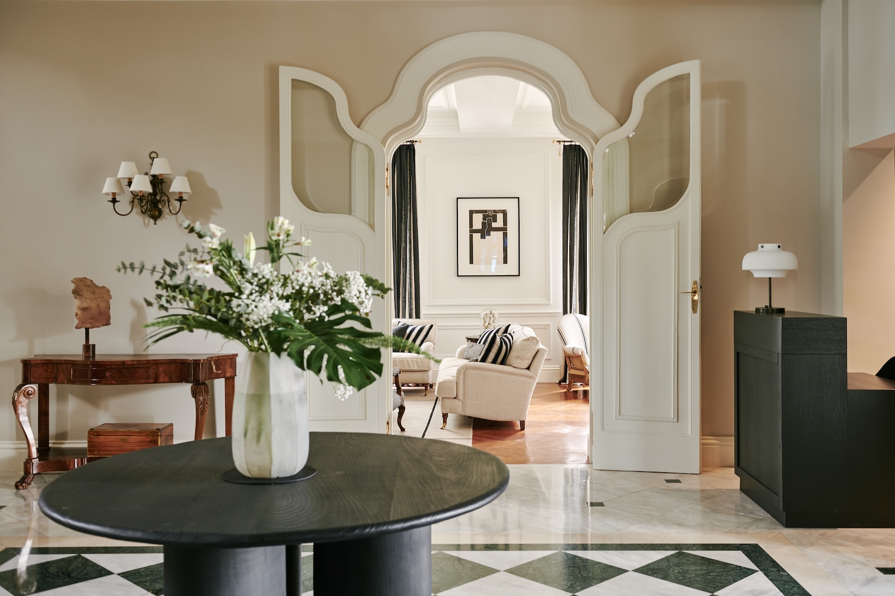 Villa Soro entrance hall with chequerboard marble floor, black round table and arched double doors to the salon | The Aficionados