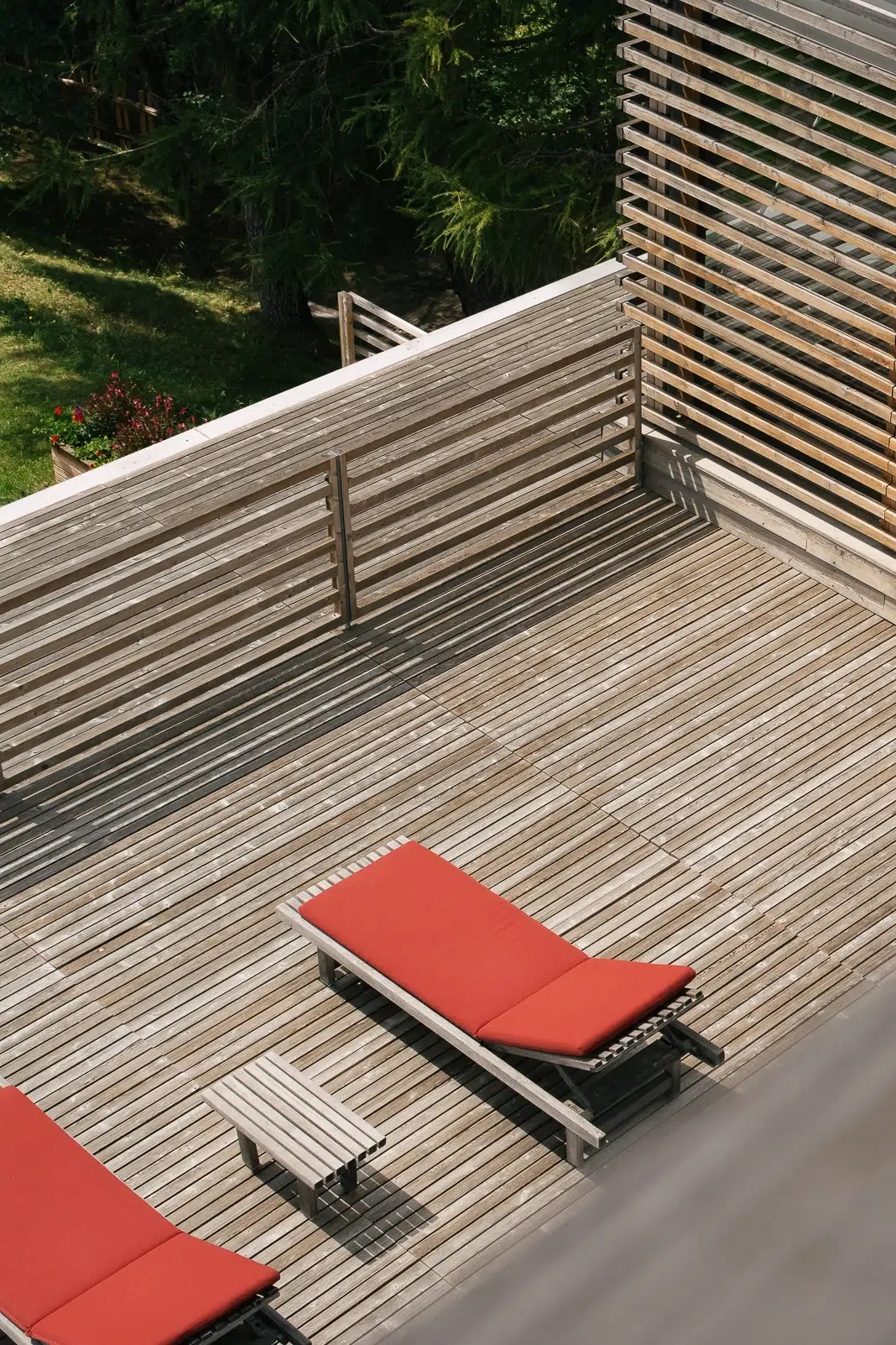 two red sun loungers out on a planked stylish decking, a verandah | vigilius mountain resort: Holistic Design & Spa Retreat in South Tyrol