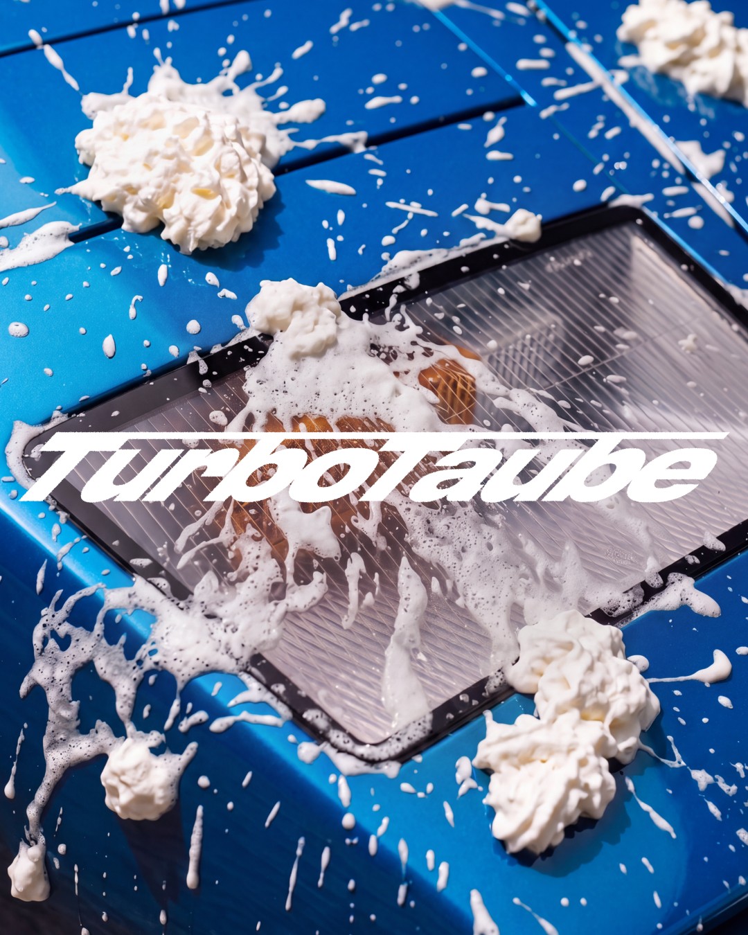 whipped-cream-blue-bonnet.jpg	Whipped cream splashed across a blue car bonnet and headlamp under the TurboTaube logo | The Aficionados