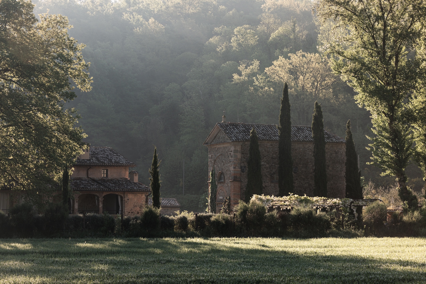 Umbrian stone monastery and farmhouse among cypresses in soft morning mist, near Vocabolo Moscatelli